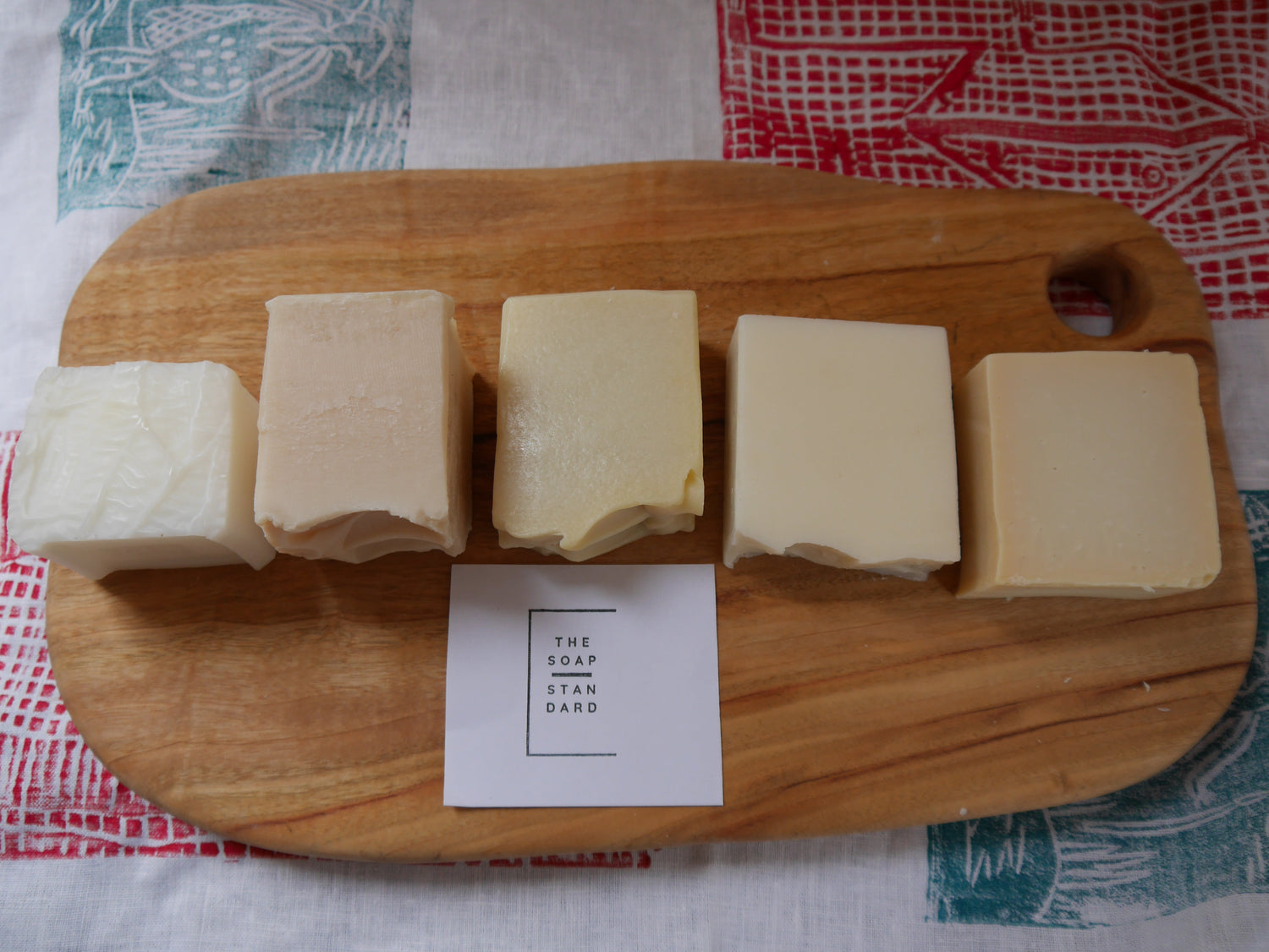 5 soap bars on a wooden board and linen cloth with Indigenous artwork