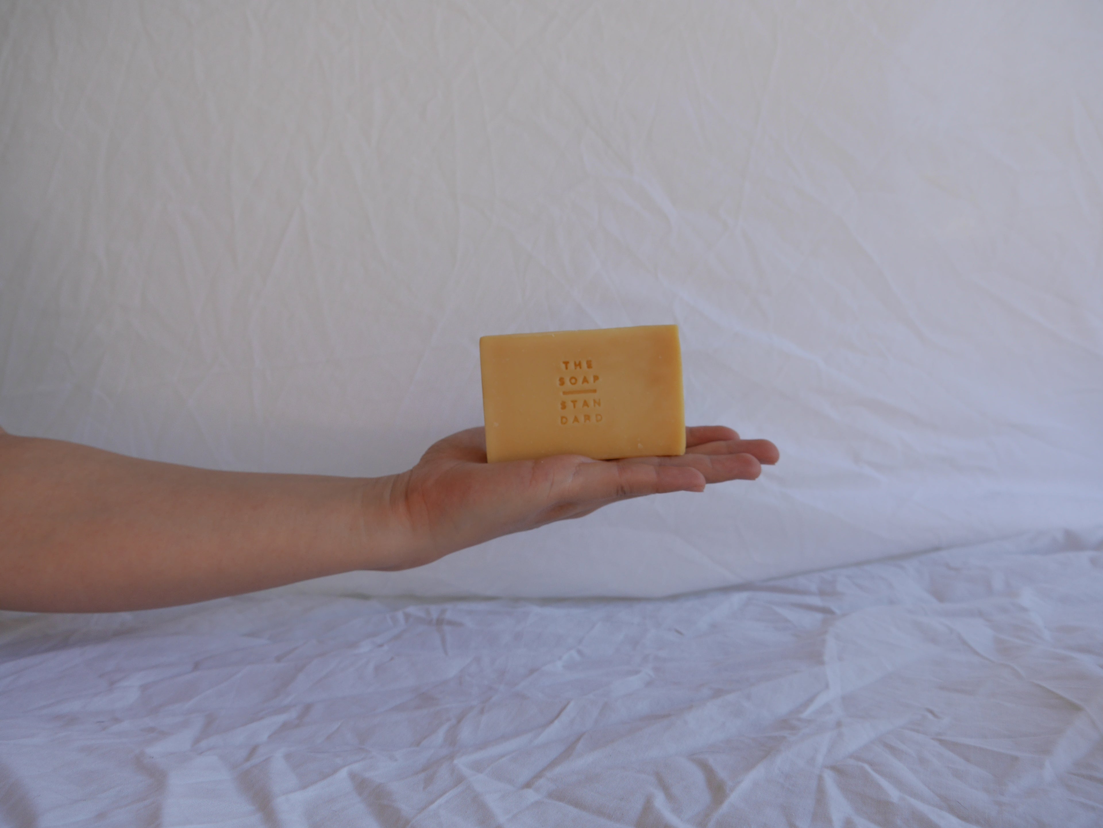 Extended arm holding soap bar on white background